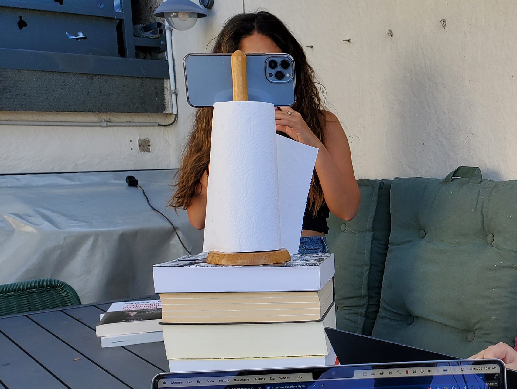 An iPhone lying horizontal across the top of a paper towel rack, stacked on four books