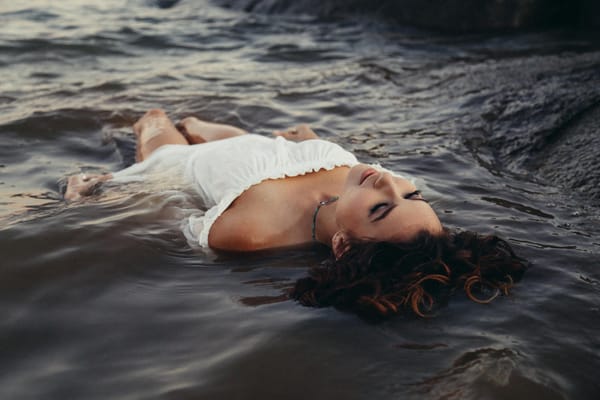 Woman lying in flowing water wearing a white dress